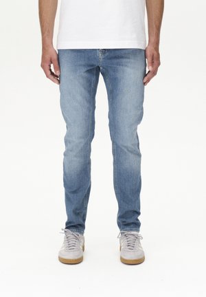 Hellblaue Denim-Jeans im Slim-Fit-Schnitt, mit einem klassischen Fünf-Taschen-Design und subtilen Ausbleichungen. Kombiniert mit grauen Sportschuhen.