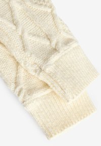 Manches de pull en tricot crème avec un motif de câble texturé, présentant des poignets côtelés et un fil doux et pelucheux pour la chaleur et le confort.