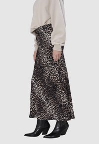 Maxi rok met luipaardprint van een vloeiende, zachte stof; gecombineerd met zwarte enkellaarsjes met hak; voorzien van een elastische tailleband voor comfort.