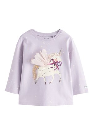 Chemise à manches longues lavande avec un imprimé licorne blanche, comprenant des ailes en tissu rose, un nœud violet et des détails dorés sur la crinière et la corne.
