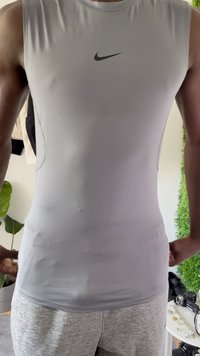 Top sin mangas de Nike en gris con un diseño ajustado, textura suave y logo negro en el pecho. Lleva puesto encima de pantalones de chándal grises.