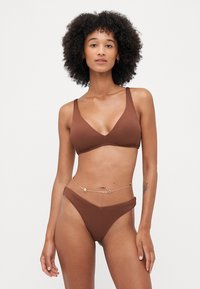 Brown ribbed bikini featuring a v-neck bralette and high-waisted bottom, accented with a gold chain belt and floral details.