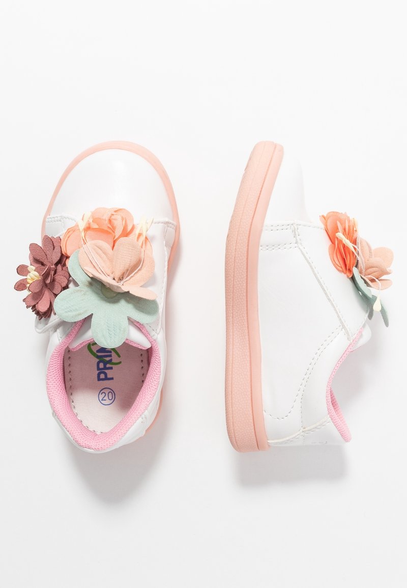 Chaussures blanches pour tout-petits avec semelles roses et doublure intérieure, décorées de fleurs en tissu multicolores sur les brides supérieures.