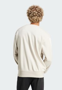 Cremefarvet sweatshirts med en afslappet pasform, der har lange ærmer og rund halsudskæring. Blød tekstur og ribbet kantdetalje.