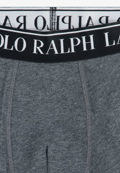 Szürke pamut boxer alsónadrág fekete rugalmas derékkal, melyen fehér színnel a "POLO RALPH LAUREN" felirat olvasható. Simaság jellemzi, testhezálló fazon.