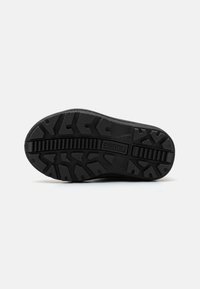 Suela de zapato de goma negra con un patrón de tracción robusto, que presenta surcos prominentes y texturas para un mejor agarre, marcada con "SOREL."