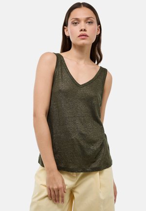 Haut sans manches vert foncé avec un col en V, en tissu brillant. Design ample avec une texture douce. Associé à un pantalon de couleur claire.