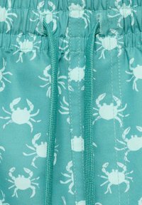 Turkos tyg med ett upprepat mönster av vita krabbor, med resårmidja som har kontrasterande dragsnöre och sömdetaljer.