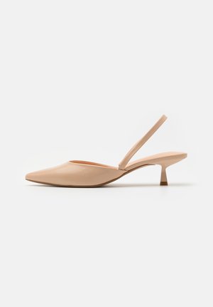 Beige spids tå slingback sko med lav kitten hæl og tynd ankelrem på hvid baggrund.
