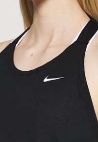 Černý sportovní tílko vyrobené z lehkého materiálu. Obsahuje bílé logo Nike, kulatý výstřih a tenké ramínka s kontrastní vnitřní barvou.