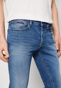 Slim fit blå denimjeans med en blektad yta. Har fem fickor, dragkedja framtill och logodetaljer på bakfickan.