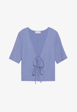 Top de punto lila claro con mangas cortas, escote en V profundo y lazo ajustable en la cintura. Tejido texturizado con sutil canalé.