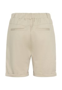 Shorts beiges cintrés avec une ceinture élastique, des revers roulés et deux poches arrière, en tissu à texture lisse.