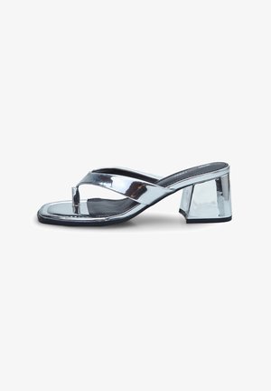 Sandale à talon en métal argenté avec un design à bout carré, présentant des brides croisées et un talon bloc pour la stabilité. Fini lisse et réfléchissant.