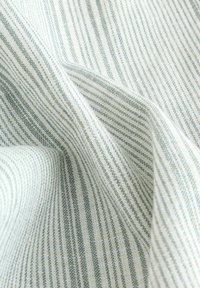 Tissu à texture douce, présentant des rayures fines alternées en gris clair et blanc, créant un motif tissé subtil.