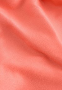Sile smooth, coral-värinen kangas, jossa on pehmeitä laskoksia ja hienovaraista tekstuuria, luoden kevyitä varjoja ja korostuksia pinnalle.