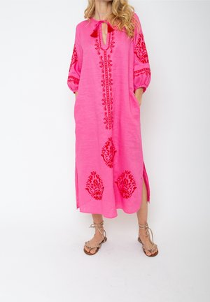 Roze linnen jurk met rode bloemenborduursels, sleutelgat-halslijn en zijsplitten. Heeft driekwart-lange pofmouwen en zakken.
