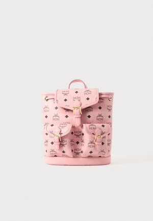 Sac à dos en cuir rose MCM avec logos noirs, trois poches avant à boucles et une poignée supérieure sur un fond clair uni.