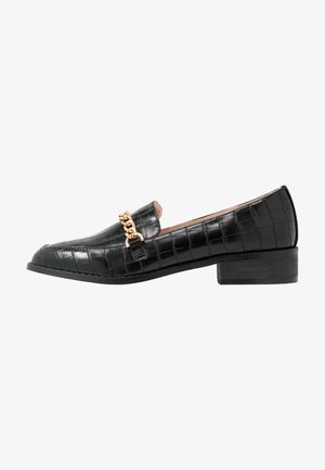 Mocassin noir en cuir à texture crocodile avec petit talon bloc et détail chaîne dorée sur le dessus.