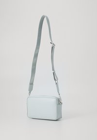 Borsa a tracolla in pelle blu chiaro di forma rettangolare, con tracolla staccabile e dettagli in metallo argentato. Texture liscia, design minimalista.
