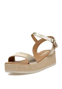Sandalias de cuña doradas metálicas con dos tiras anchas, con una superficie texturizada y un tacón de cuña similar al yute natural.