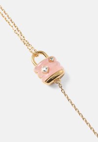 Colar de corrente de ouro com um pendente em forma de fecho rosa com acabamento brilhante, dois pequenos acentos semelhantes a diamantes e a inscrição "GUESS".