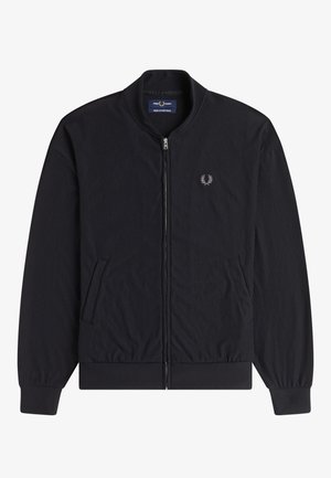 Chaqueta negra de pana con cremallera, cuello, puños y dobladillo acanalados, que cuenta con dos bolsillos delanteros y un pequeño logo bordado en el pecho.