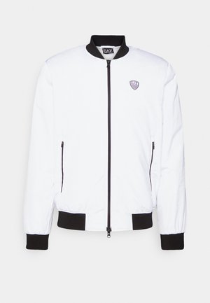 Weiße Bomberjacke mit schwarzem Kragen und Bündchen, Reißverschluss, zwei seitlichen Reißverschlusstaschen und einem kleinen Logo im linken Brustbereich.