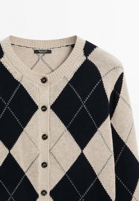 Beige en marineblauwe argyle gebreide cardigan met ronde hals en zwarte knopen aan de voorkant, toont het bovenste deel en de mouw.