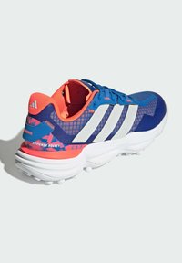 Blue and pink athletic shoe with mesh upper, white stripes, and textured heel. Features a cushioned sole and pronged outsole for grip.