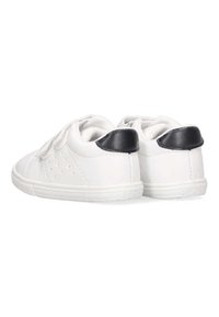 Zapatillas de cuero blancas con acentos de tacón negro, que presentan detalles perforados en los laterales y una suela de goma texturizada.