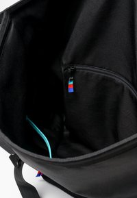 Vnitřek černé textilní tašky s kapsou na zip, která má červenou, bílou a modrou visačku. Obsahuje také tyrkysovou kapsu na zip.