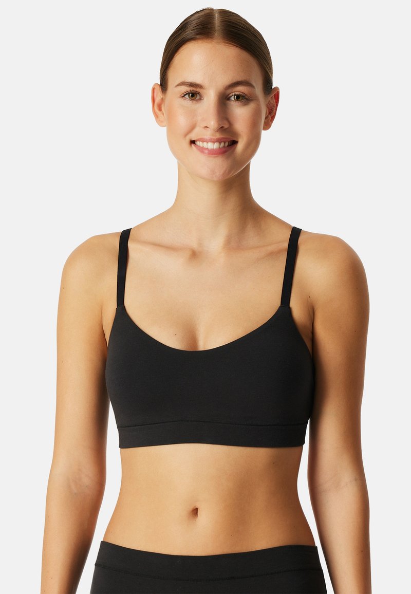Svart bralette med tunna axelband, rundad halsringning och sömlös design. Tillverkad av mjukt, stretchigt material för komfort. Inga synliga detaljer.