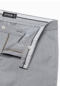 Har grayit housut, joissa on vetoketju ja nappisulku, raidoitettu sisävuori ja sileä kangasrakennus. Tunnuksessa lukee "ombre quintessence."