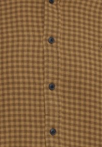 Camisa de cuadros marrón hecha de tela con botones negros, que cuenta con un frente con botones y detalles de costura sutiles a lo largo del placket.