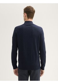 Marineblauer Strickpullover mit hohem Kragen, langen Ärmeln und gerippten Bündchen. Glatte Textur, einfaches Design und keine sichtbaren Muster oder Akzente.
