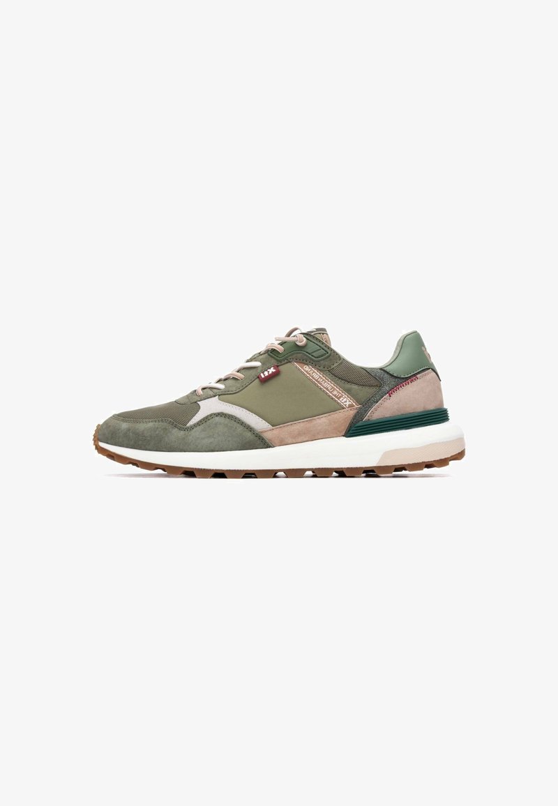 Zapatillas deportivas verdes y beige con materiales de ante y malla, una entresuela blanca y una suela exterior gruesa de goma con patrones de agarre texturizados.