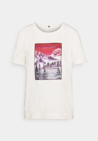 Bílá bavlněná trička s potiskem horské krajiny v purpurové, červené a modré barvě, s logem "TOMMY HILFIGER" ve spodní části. Krátké rukávy.