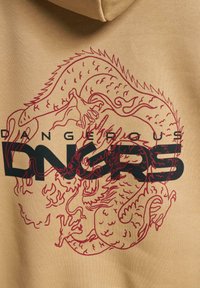 Sudadera beige con un gráfico de dragón rojo de detalles intrincados y un texto en negrita negro que dice "DANGEROUS DNGRS". Textura suave.