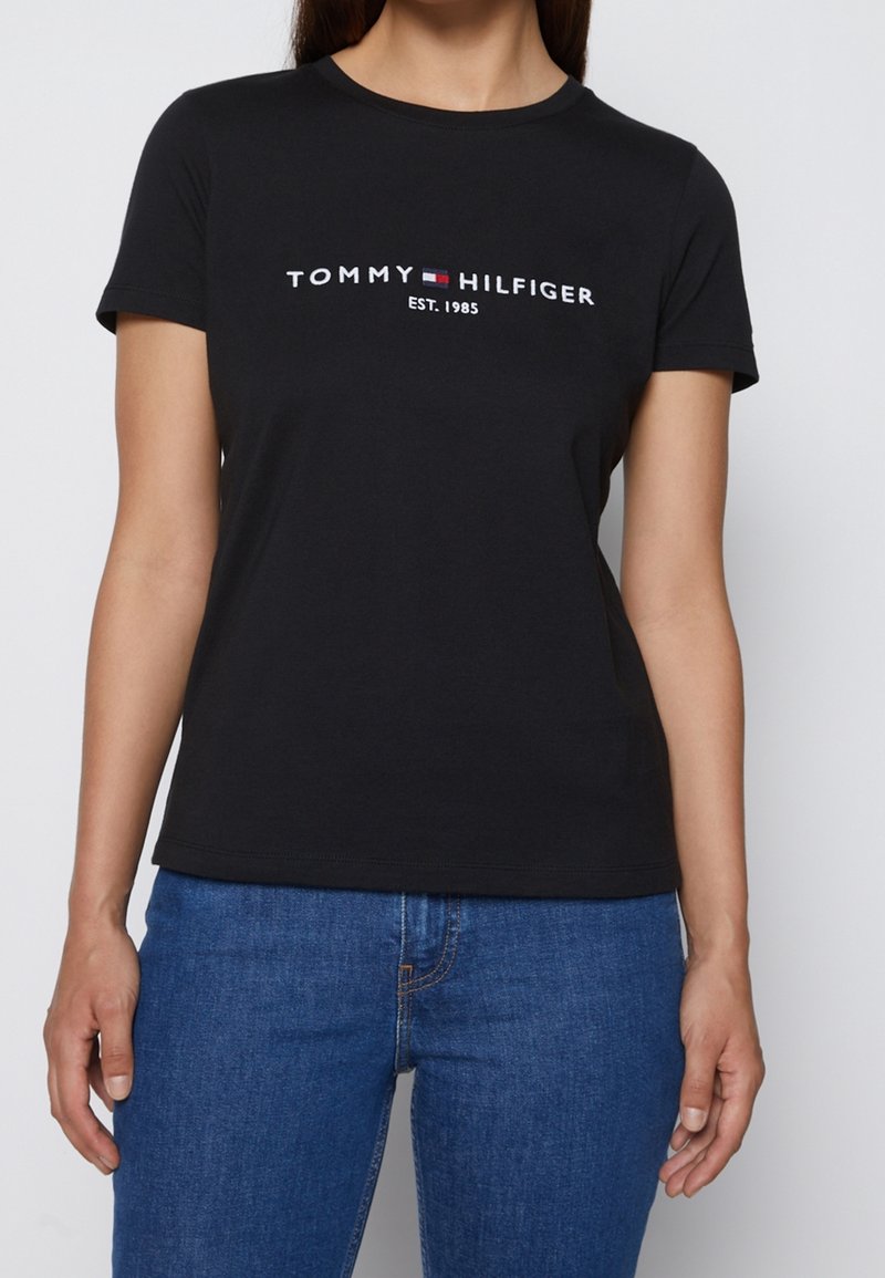 Černé bavlněné tričko s krátkými rukávy, kulatým výstřihem a bílým logem 'TOMMY HILFIGER' s červeným a modrým akcentem. Přiléhavý střih.