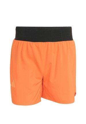 Pomarańczowe sportowe szorty z szerokim czarnym elastycznym pasem i małym odblaskowym logo na dolnej lewej nogawce.