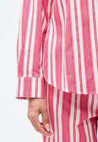 Κόκκινη και λευκή βαμβακερή μπλούζα για χαλάρωση με μακριά μανίκια και λεπτομέρεια μανσαέτας, συνδυασμένη με αντίστοιχο ριγέ παντελόνι. Λείο υφής.