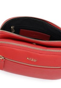 Czerwona torebka syntetyczna o teksturowanym wykończeniu, z detalami w kolorze złotym przy zamku błyskawicznym oraz logo. Wnętrze zawiera czarne wykończenie i małą kieszeń na zamek.