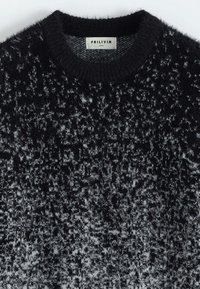 Pull en tricot noir et gris avec une texture duveteuse, arborant un motif moucheté et un col rond. Étiquette indique "FRILIVIN, Taille M."