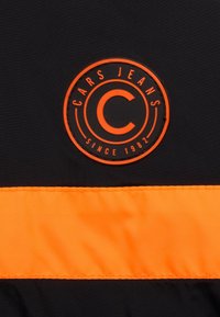 Black fabric with a bright orange horizontal stripe. Central round logo features "CARS JEANS" and "SINCE 1982" in black and orange. Durable texture.