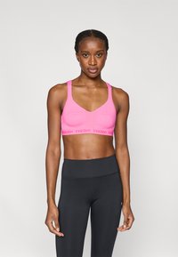 Ροζ αθλητικό μπουστάκι με αεριζόμενο σχέδιο με οπές, ρυθμιζόμενους ιμάντες και ελαστική ζώνη με λογότυπο. Συνδυάζεται με μαύρο κολάν ψηλής μέσης.