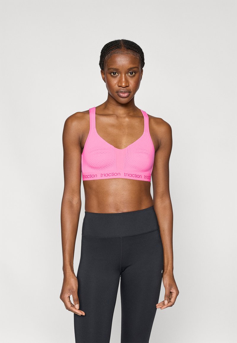 Ροζ αθλητικό μπουστάκι με αεριζόμενο σχέδιο με οπές, ρυθμιζόμενους ιμάντες και ελαστική ζώνη με λογότυπο. Συνδυάζεται με μαύρο κολάν ψηλής μέσης.