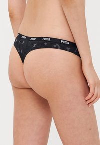 Crne tange s kamuflažnim uzorkom, s mekanim elastičnim pojasom s "PUMA" brandingom. Glatka tekstura, prilagođen dizajn.