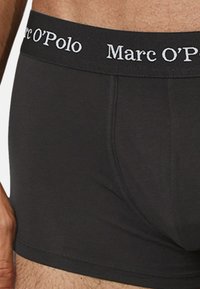 Schwarze Boxershorts mit eng anliegender Passform, ausgestattet mit einem weichen Bund, der in Weiß "Marc O’Polo" geprägt ist. Glattes Baumwollmaterial.