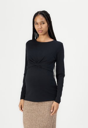 Maglietta premaman nera a maniche lunghe con dettaglio annodato davanti, realizzata in tessuto morbido ed elasticizzato per comfort e una silhouette aderente.